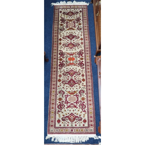 25 - A beige ground Kazak runner with multicoloured geometric patterned ground within multicoloured borde... 