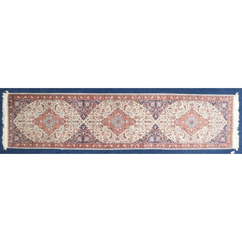 67 - An ivory ground Keshan style runner with three red diamond shaped medallions, blue spandrels on flor... 