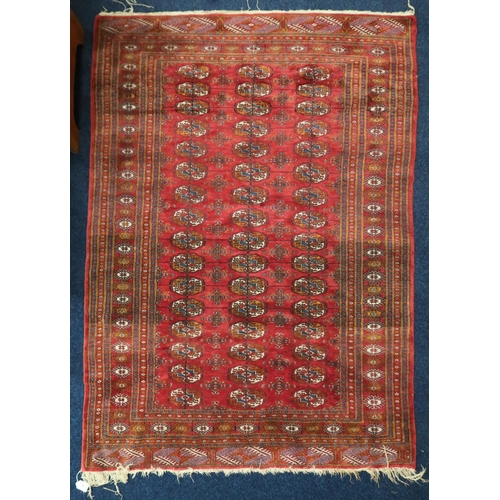 10 - A red ground fine pile Pakistani Bokara rug with all-over lozenge patterned ground within multicolou... 