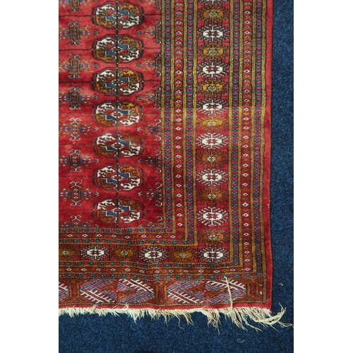 10 - A red ground fine pile Pakistani Bokara rug with all-over lozenge patterned ground within multicolou... 