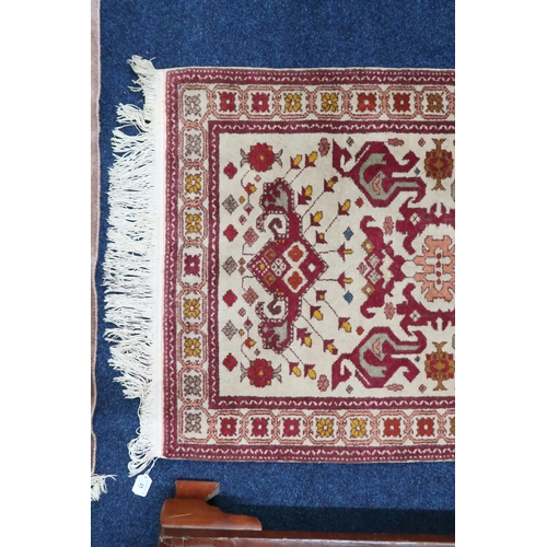 25 - A beige ground Kazak runner with multicoloured geometric patterned ground within multicoloured borde... 