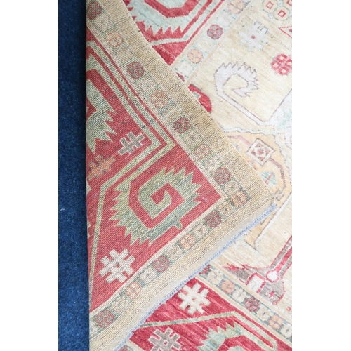 3 - A beige ground Kazak rug with multicoloured geometric patterned ground within terracotta border, 281... 