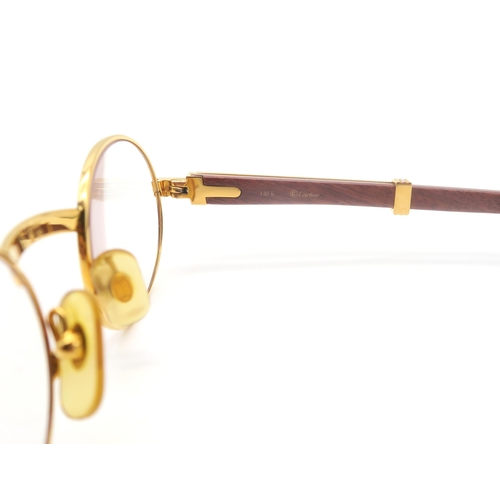 436 - A pair of Cartier gold-tone glasses, with wooden temples, the bridge marked 