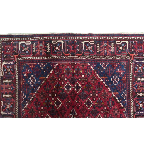 2184 - A DARK RED JOSHAGAN RUG with dark blue diamond medallion and matching spandrels on geometric pattern... 