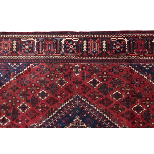 2184 - A DARK RED JOSHAGAN RUG with dark blue diamond medallion and matching spandrels on geometric pattern... 