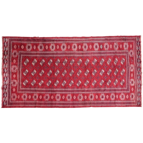 2185 - A RICH RED GROUND TURKMAN RUG with all-over lozenge design within geometric patterned border, 383cm ... 