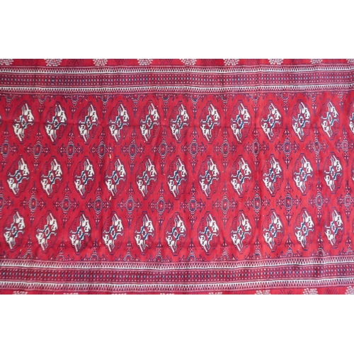 2185 - A RICH RED GROUND TURKMAN RUG with all-over lozenge design within geometric patterned border, 383cm ... 