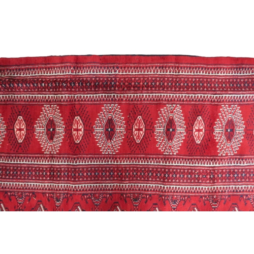 2185 - A RICH RED GROUND TURKMAN RUG with all-over lozenge design within geometric patterned border, 383cm ... 