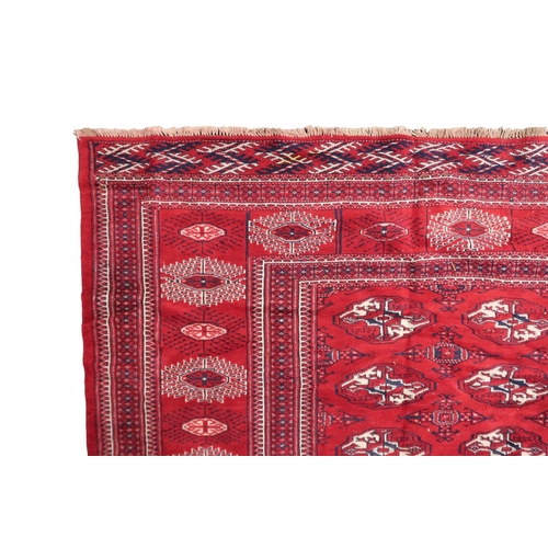 2185 - A RICH RED GROUND TURKMAN RUG with all-over lozenge design within geometric patterned border, 383cm ... 