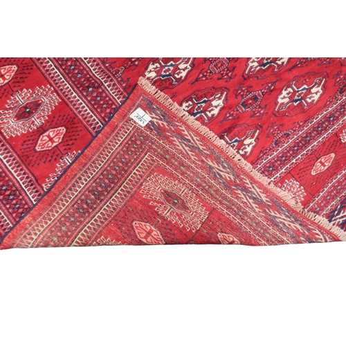 2185 - A RICH RED GROUND TURKMAN RUG with all-over lozenge design within geometric patterned border, 383cm ... 