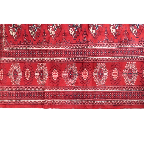 2185 - A RICH RED GROUND TURKMAN RUG with all-over lozenge design within geometric patterned border, 383cm ... 