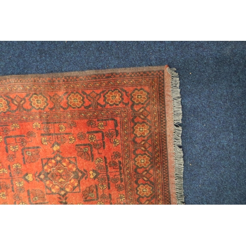 24 - A red ground Hamadan rug with multicoloured geometric patterned ground within multicoloured floral b... 