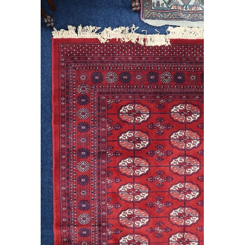 4 - A large red ground Bokhara style rug with all-over lozenge design within multicoloured geometric bor... 