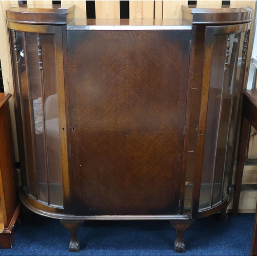 65 - A 20th century oak display cabinet with central cabinet door flanked by bowed glazed doors on shaped... 