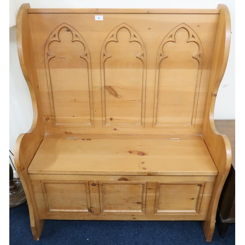 95 - A 20th century pine Gothic style hall settle with shaped back over hinged seat, 113cm high x 96cm wi... 