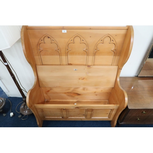 95 - A 20th century pine Gothic style hall settle with shaped back over hinged seat, 113cm high x 96cm wi... 