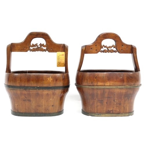 2021 - A PAIR OF 20TH CENTURY CHINESE HARDWOOD WATER CARRIERS with carved pierced carry handles over cooper... 