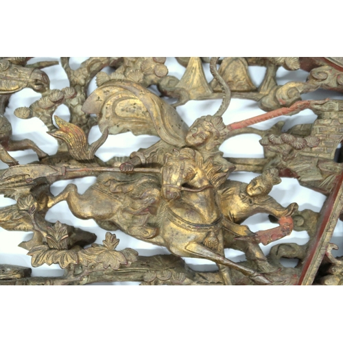 2024 - A 20TH CENTURY CHINESE GILTWOOD CARVED DECORATIVE WALL PANEL depicting Chinese warriors on horseback... 