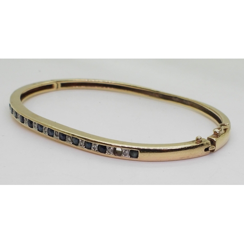 718 - A 9ct gold sapphire and diamond accent bangle (one sapphire missing) weight 9.9gms