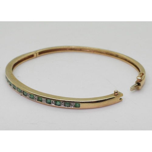 719 - A 9ct gold emerald and diamond accent bangle, weight 9.5gms