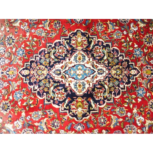 1 - A red ground Keshan rug with dark blue and cream central medallion and matching spandrels on floral ... 