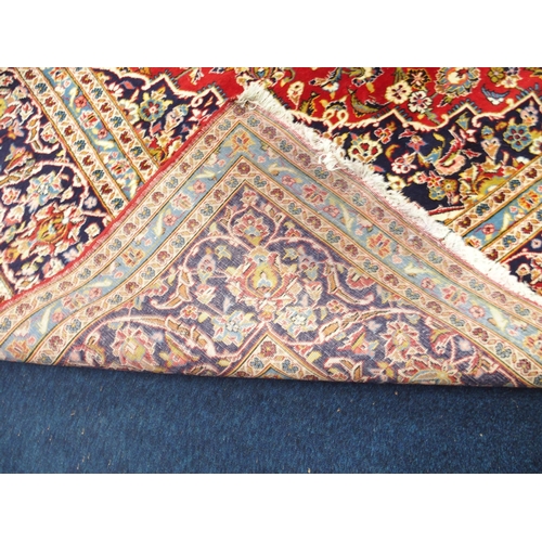 1 - A red ground Keshan rug with dark blue and cream central medallion and matching spandrels on floral ... 