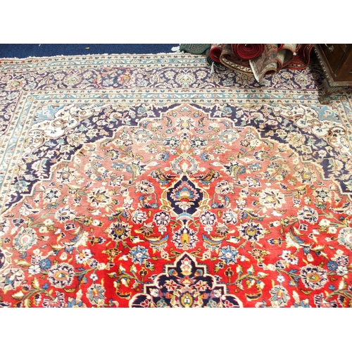 1 - A red ground Keshan rug with dark blue and cream central medallion and matching spandrels on floral ... 