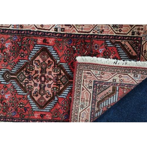 32 - A red ground Hamadan rug with pink diamond shape central medallion and matching spandrels on geometr... 