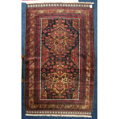 35 - A dark ground Balouch rug with two beige geometric medallions within multiple multicoloured borders,... 