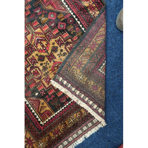 35 - A dark ground Balouch rug with two beige geometric medallions within multiple multicoloured borders,... 