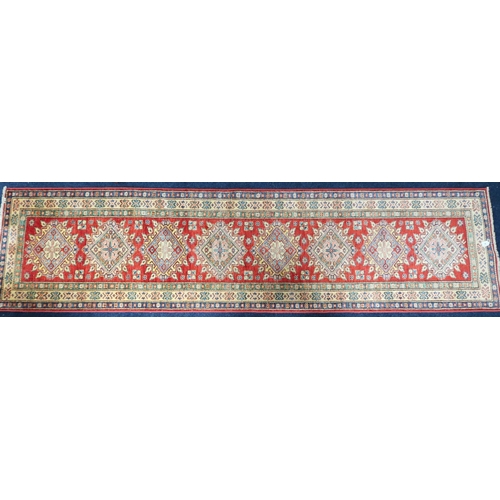 48 - A red ground Heriz runner with multicoloured geometric medallions within multiple multicoloured bord... 