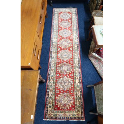 48 - A red ground Heriz runner with multicoloured geometric medallions within multiple multicoloured bord... 