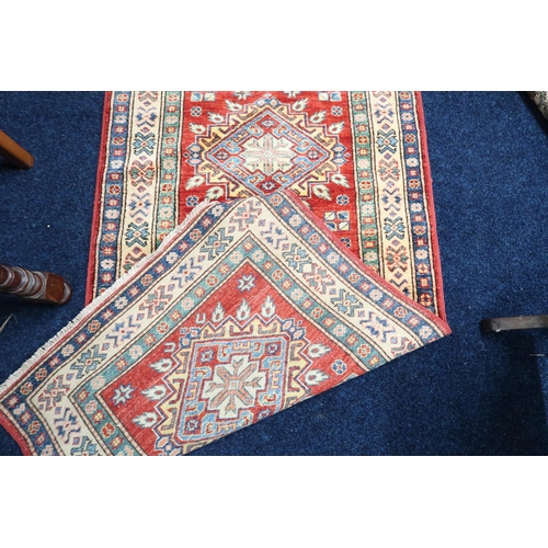 48 - A red ground Heriz runner with multicoloured geometric medallions within multiple multicoloured bord... 