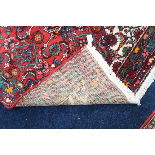 51 - A deep pile wool red ground Hamadan rug with dark central medallion and cream spandrels on geometric... 