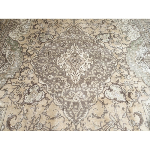 6 - A large beige ground Tabriz carpet with darker central medallion and spandrels on floral/foliate pat... 