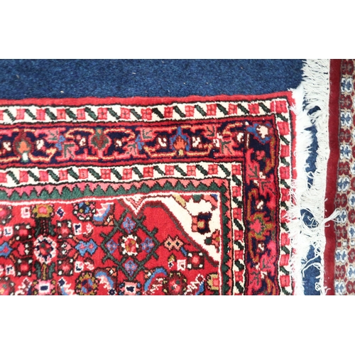 60 - A red ground Hamadan rug with cream central medallion and matching spandrels on multicoloured geomet... 