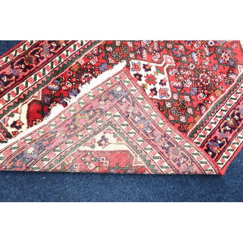 60 - A red ground Hamadan rug with cream central medallion and matching spandrels on multicoloured geomet... 