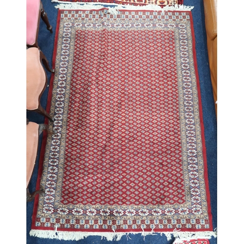 61 - A red ground Araak rug with geometric patterned ground within multicoloured lozenge patterned border... 