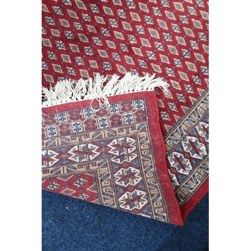 61 - A red ground Araak rug with geometric patterned ground within multicoloured lozenge patterned border... 