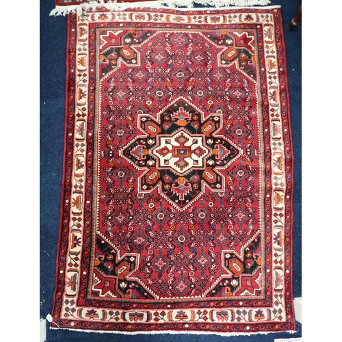 62 - A red ground Heriz rug with dark blue central medallion and matching spandrels on geometric patterne... 