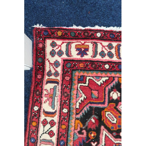 62 - A red ground Heriz rug with dark blue central medallion and matching spandrels on geometric patterne... 