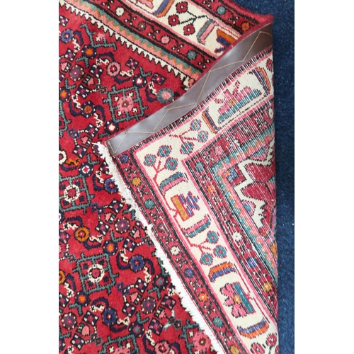 62 - A red ground Heriz rug with dark blue central medallion and matching spandrels on geometric patterne... 