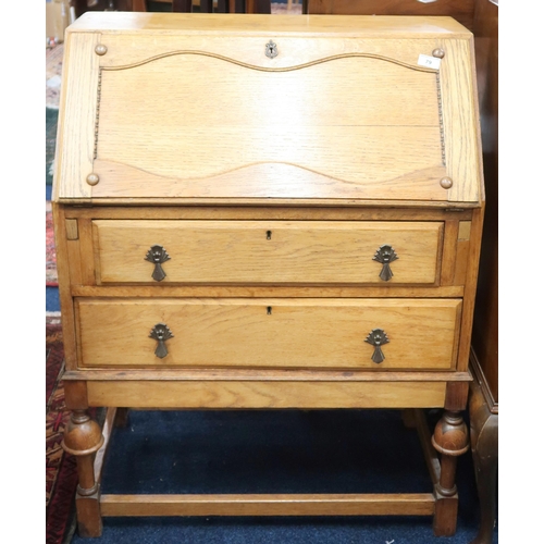 79 - A 20th century blonde oak writing bureau with fall front writing compartment over two long drawers o... 