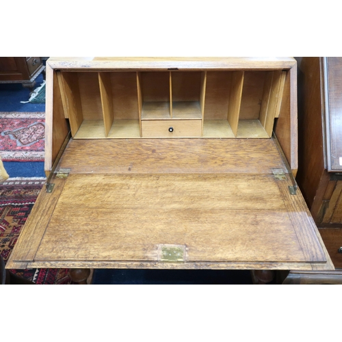 79 - A 20th century blonde oak writing bureau with fall front writing compartment over two long drawers o... 