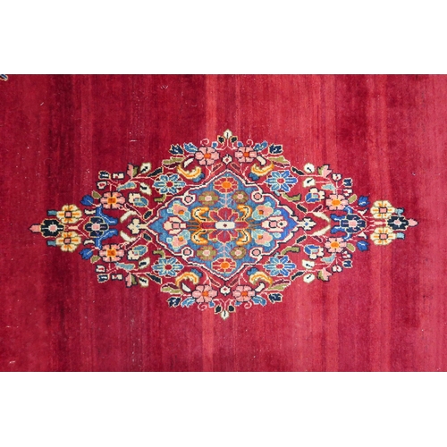 86 - A deep red ground Bijar rug with multicoloured floral pattern central medallion and spandrels within... 