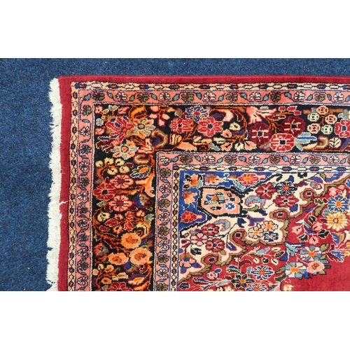 86 - A deep red ground Bijar rug with multicoloured floral pattern central medallion and spandrels within... 