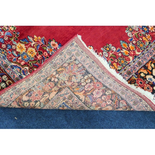 86 - A deep red ground Bijar rug with multicoloured floral pattern central medallion and spandrels within... 