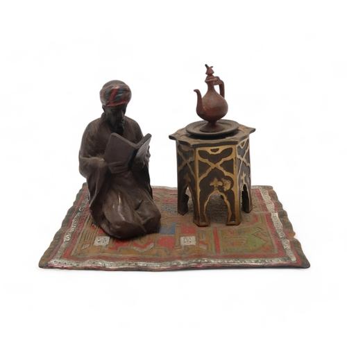 216 - A 20th century after Bergman cold painted bronze inkwell modelled as a kneeling Turkish man reading ... 