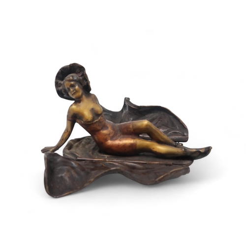 217 - A 20th century after Bergman cold painted bronze figurine of a reclining scantily clad lady, with a ... 