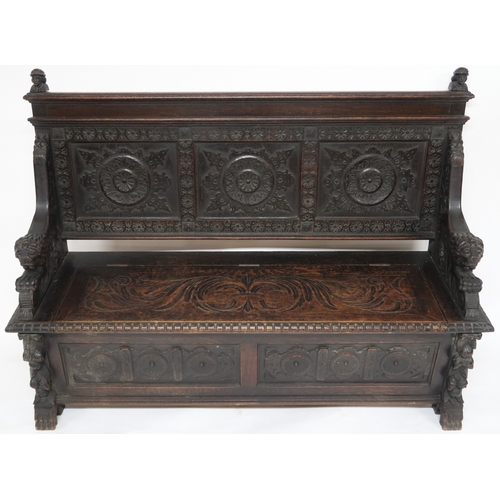 2001 - A 19TH CENTURY STAINED OAK GOTHIC STYLE SETTLE panel back carved with circular reliefs capped with t... 